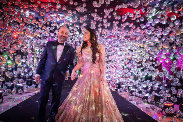 A couple celebrating against a colourful floral wall